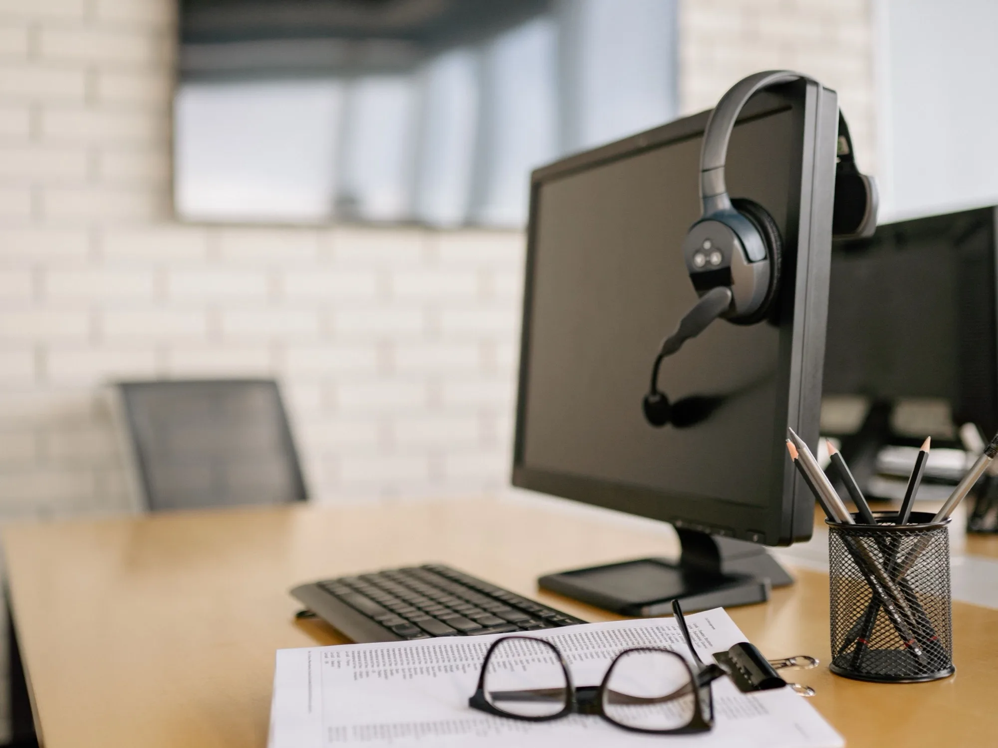 Schreibtisch mit Bildschirm, Headset und einem Ausdruck